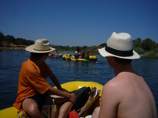 Niños de una familia usando sombreros y disfrutando de su tiempo haciendo rafting 