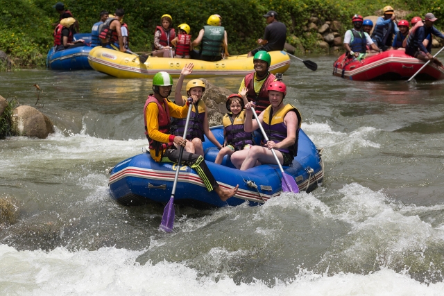  Diferentes familias usando equipo amarillo y azul haciendo rafting