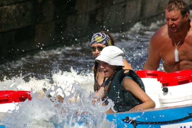 Niña con sombrero blanco divirtiéndose mientras hace rafting con su familia