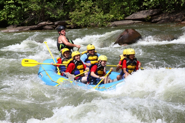 Niños usando equipo rojo mientras hacen rafting