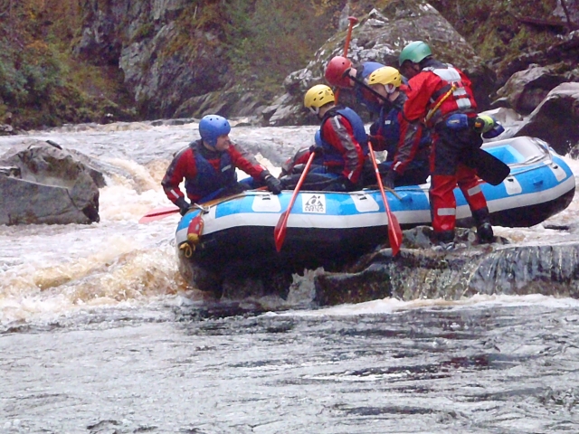 Personas con cascos amarillos y azules mientras practican rafting 