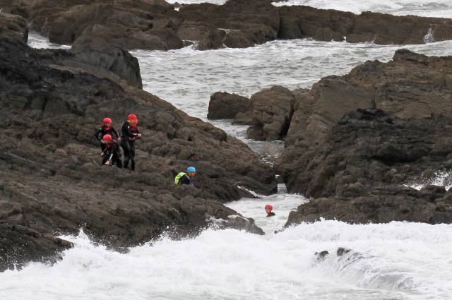  4 personas con trajes de neopreno negros y cascos azules y rojos mientras nadan 
