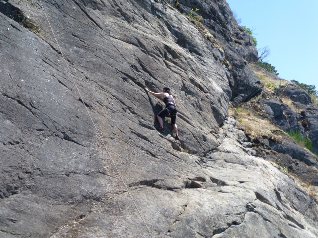 Mujer escalando un acantilado duranle su experiencia de Coasteering
