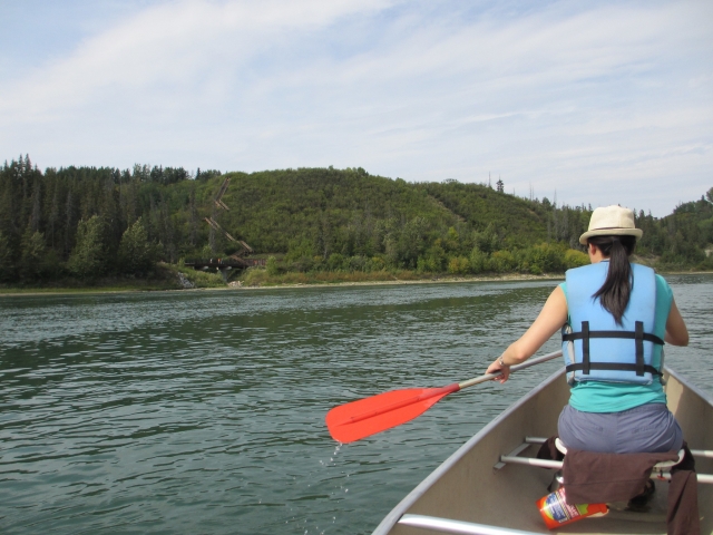  Mujer con sombrero y ayudas de flotabilidad azules navegando en canoa en el río 