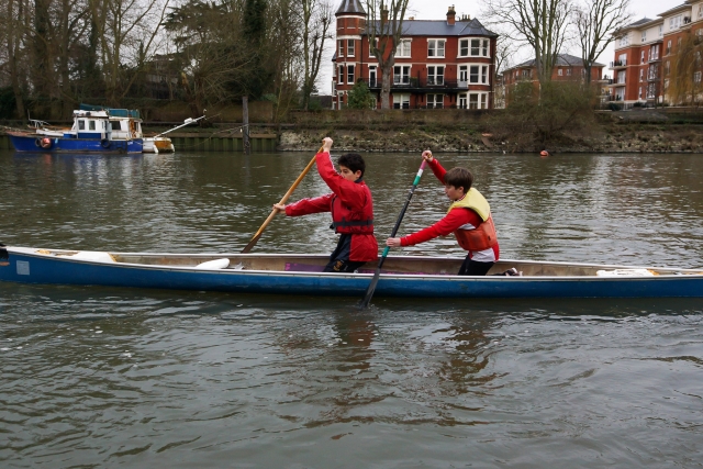 Dos niños navegando en canoa con ayudas de flotabilidad amarillas y ropa roja 
