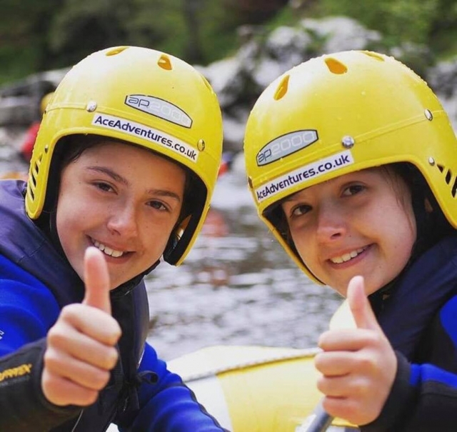  Niños con cascos amarillos y flotadores azules divirtiéndose haciendo barranquismo con nosotros 