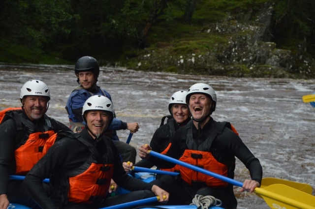 Familia feliz vistiendo ayudas de flotabilidad naranja y trajes negros piragüismo