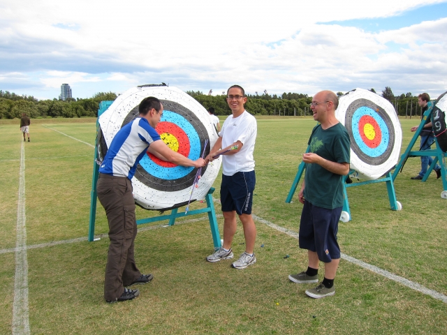  Grupo de hombres practicando jalo con arco como parle de su curso para principiantes