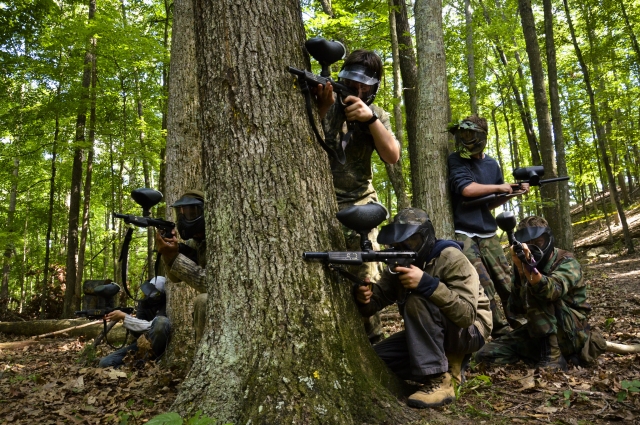 Grupo de 6 personas jugando gotcha y vistiendo traje de camuflaje 