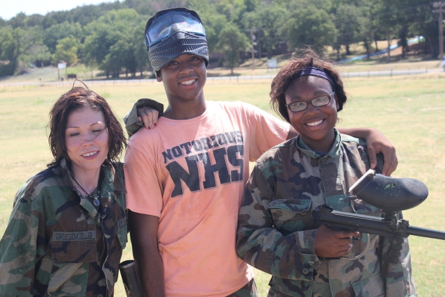 Tres amigos, dos de ellos con trajes de camuflaje, jugando gotcha