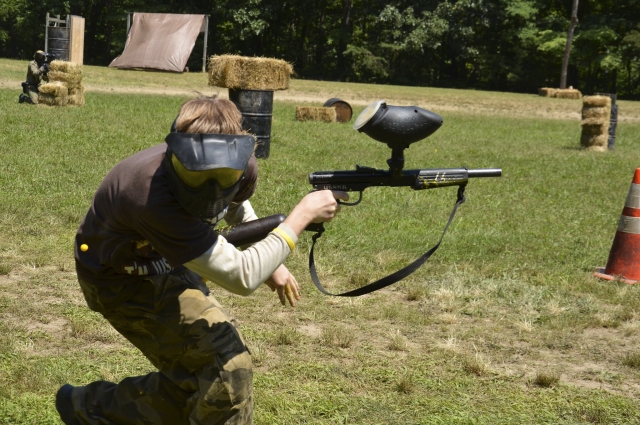 Niño con playera negra y pantalón de camuflaje jugando paintball