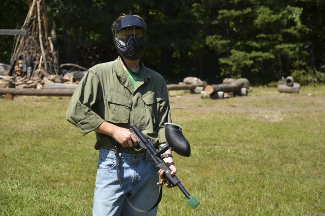  Niño con máscara protectora, camisa verde y jeans mientras juega paintball