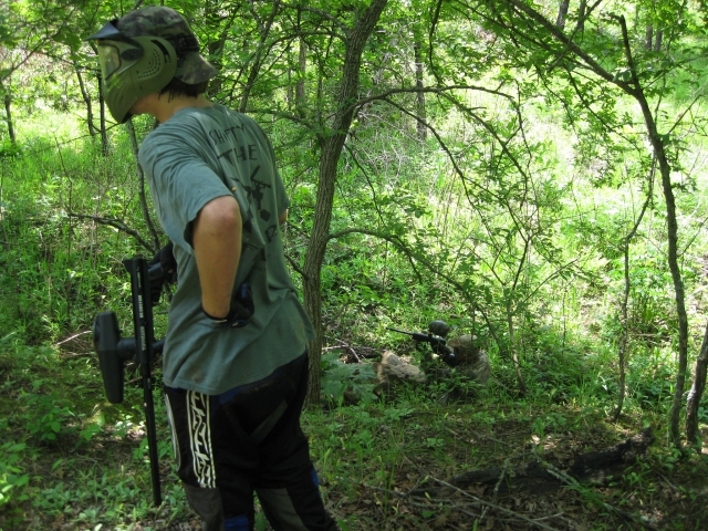  Niño con playera verde jugando gotcha en el bosque 