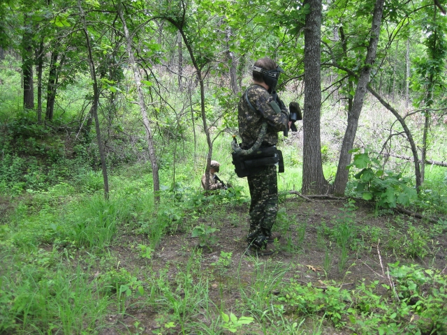 Jugador de gotcha con traje de camuflaje listo para disparar 