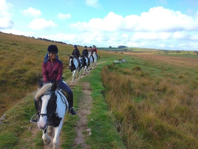  5 personas subiendo caballos blancos y negros divirtiéndose y sonriendo 
