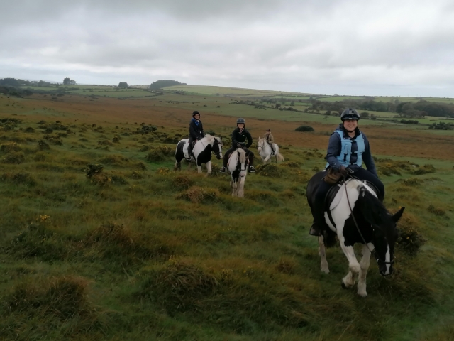  4 mujes con suétes azules divirtiéndose subiendo a caballo