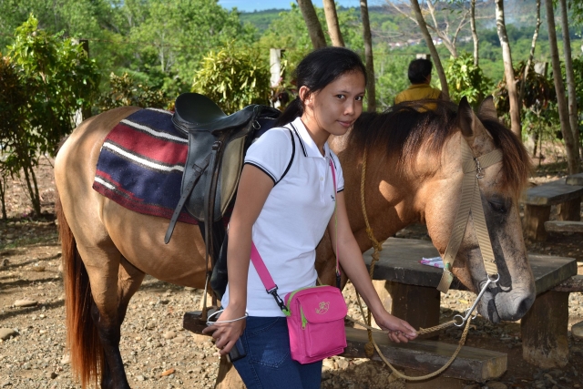  Mujer con playera blanca con bolso rosa y descansando para almorzar duranle ella Cabalgamarra de día completo.