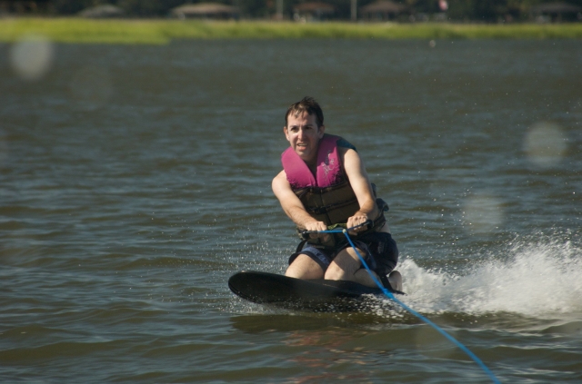 Hombre con ayudas de flotabilidad rosa haciendo esquí acuático