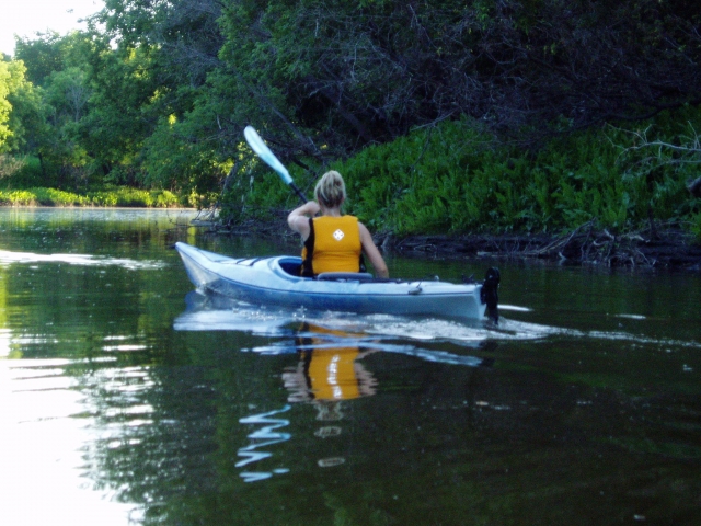 Mujer usando ayudas de flotabilidad amarillas haciendo kayak