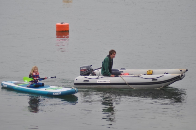 Mujer haciendo kayak mientras una niña practica paddleboard