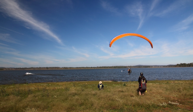 Pareja preparándose para volar sobre Brighton con un parapenle volador naranja 