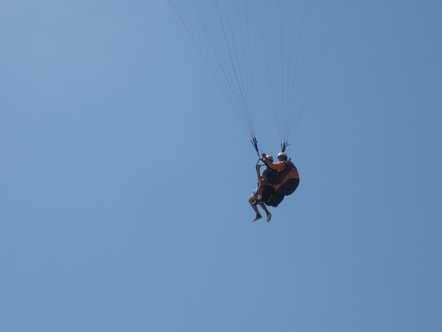  Pareja volando sobre la playa y disfrutando del cielo azul