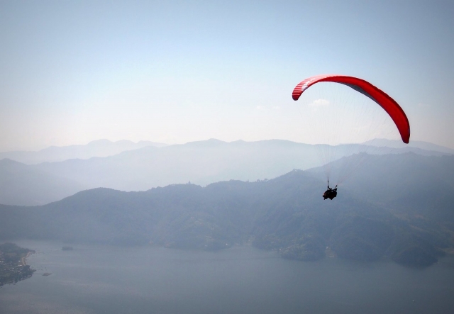  Persona disfrutando de la vista desde un parapenle volador rojo 