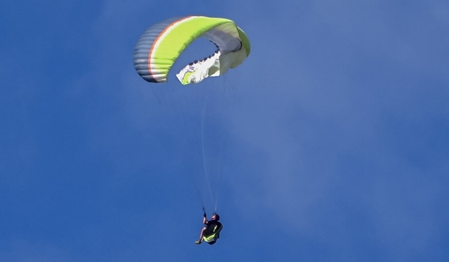  Persona volando en parapenle volador azul, blanco y verde 
