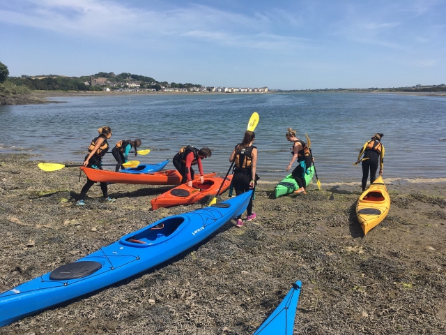  Grupo de personas llevando los kayaks al agua para realizar nuestra experiencia de kayak tándem.