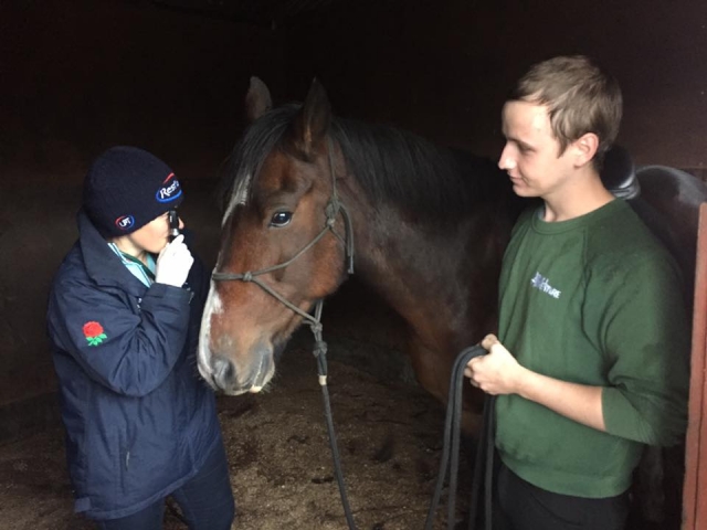 Hombre con playera verde y niño con suéter negro cuidando un caballo antes de salir a su paseo