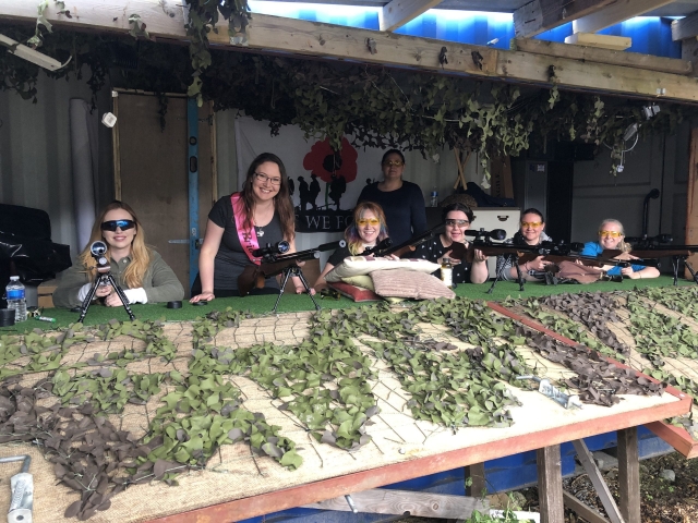 Grupo de amigos grils con lentes protectoras a punto de disparar sus rifles 