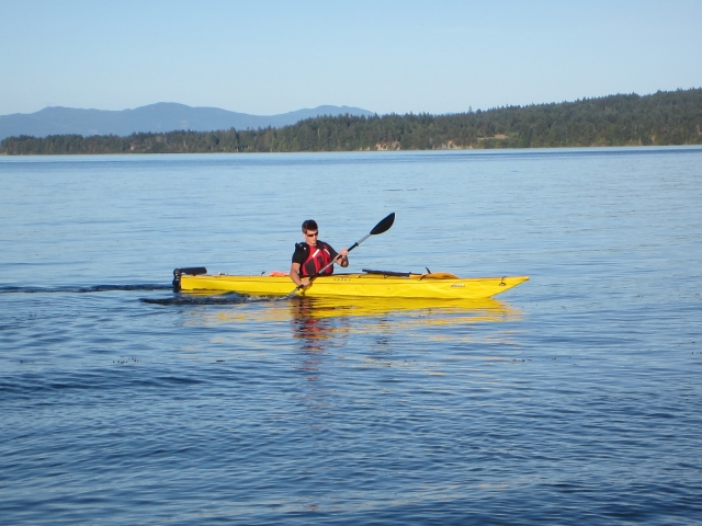  Niño con ayudas de flotabilidad rojas navegando en un kayak amarillo 