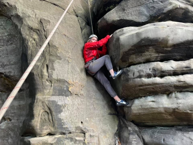  Mujer con suéter rojo y jeand escalando 
