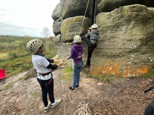 Tres niños con cascos blancos escalando 