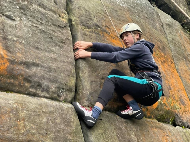  Niño con suéter negro y casco blanco escalando 