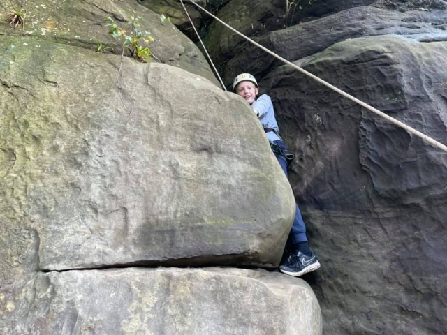  Niño con suéter gris y casco blanco escalando 