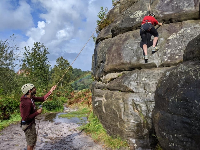  Dos personas con cascos blancos escalando duranle su experiencia de escalada en grupo 