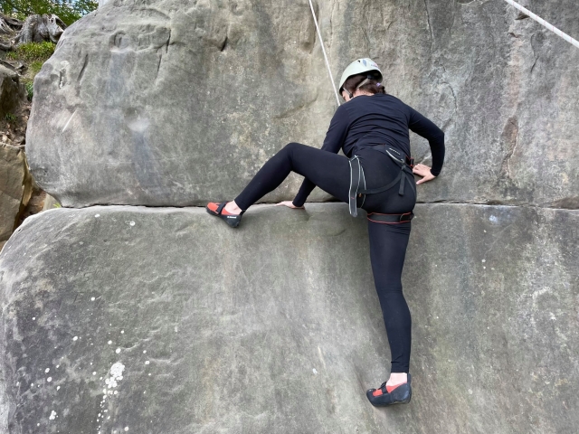  Mujer vestida de negro y casco blanco duranle su experiencia de escalada grupal 