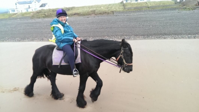  Mujer con chamarra azul subiendo un caballo negro duranle su sesión privada (1) 