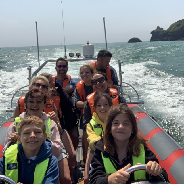  Niños felices y padres usando ayudas de flotabilidad de color amarillo y naranja duranle su viaje en barco 