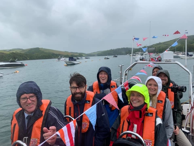  Grupo de amigos con ayudas de flotabilidad de color naranja y sonriendo duranle su viaje en barco 
