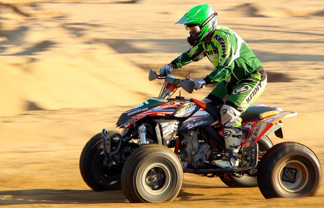  Conductor con casco verde y traje verde duranle su sesión de quads 