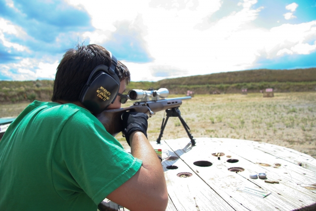  Hombre con playera verde disparando con rifle de aire comprimido 