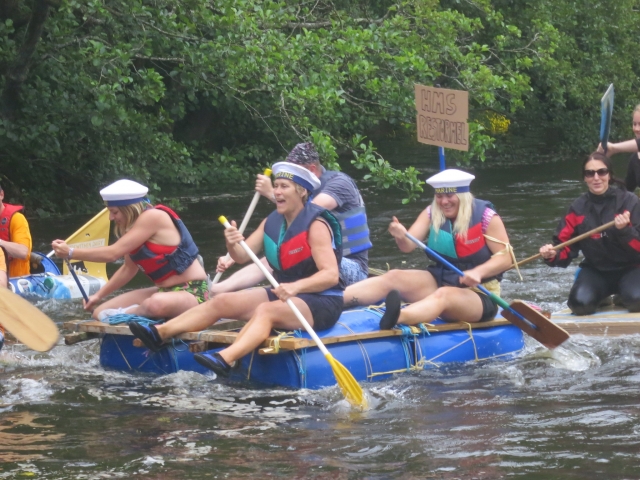  Personas sonriendo duranle su carrera de rafting usando ayudas de flotabilidad rojas 