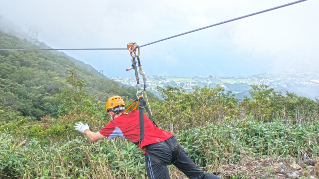  Hombre con casco amarillo y playera roja duranle su experiencia de tirolesa 