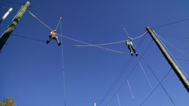  Niño y niña con casco rojo en el aire caminando sobre obstáculos de madera y cuerdas