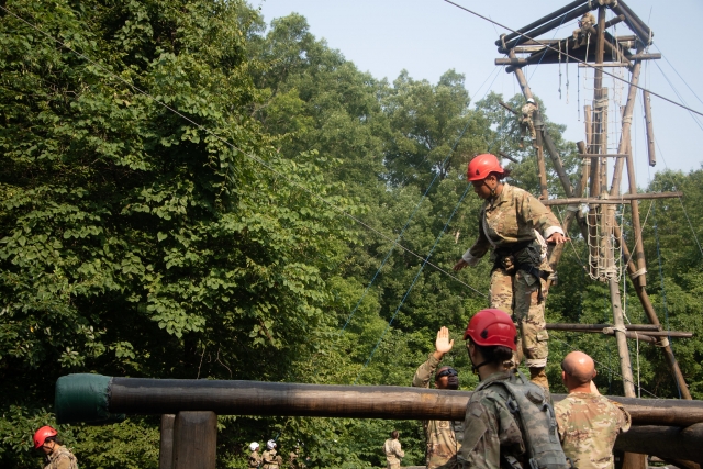 Hombre con casco rojo y traje de camuflaje cruzando un obstáculo de madera 