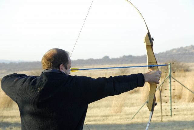 Hombre con suéter negro haciendo jalo con arco
