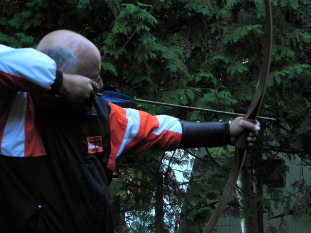 Hombre con suéter naranja y negro haciendo jalo con arco
