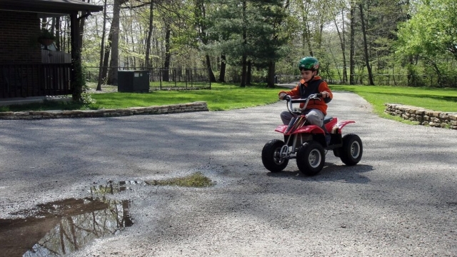  Niño con casco azul y subiendo un cuatrimoto rojo